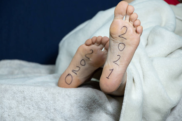 2021 et 2021 est écrit sur les pieds féminins d'une fille couchée sur un lit à la maison dans une chambre - Photo, image