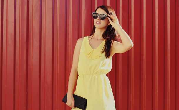 Portrait of beautiful young woman in yellow dress over a red background - 写真・画像