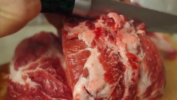 Τα γυναικεία χέρια κόβουν το κρέας σε κομμάτια από κοντά. Κομμάτι κρέας από κοντά σε μια ξύλινη σανίδα. Προετοιμασία των τροφίμων. - Πλάνα, βίντεο