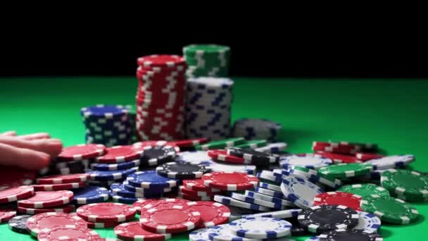 Το χέρι μετράει μάρκες πόκερ που βρίσκονται σε ένα πράσινο τραπέζι σε μαύρο φόντο σε κοντινό πλάνο - Πλάνα, βίντεο