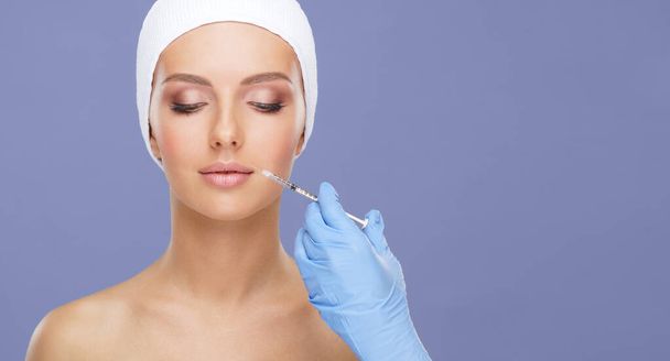 Doctor injecting in a beautiful face of a young woman. Plastic surgery, skin lifting and aesthetic medicine concept. - Fotó, kép