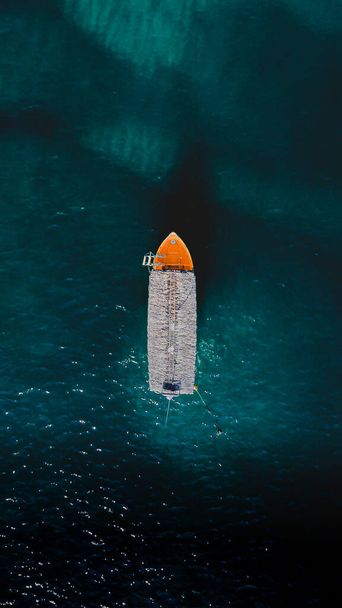 Κηφήνας πλάνο ενός πορτοκαλί tour boat στη μέση της θάλασσας του Κορτέζ - Φωτογραφία, εικόνα