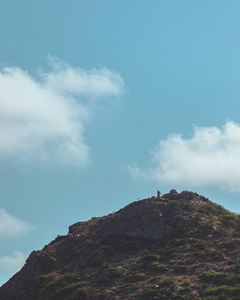 Homme méconnaissable au sommet d'une montagne avec un ciel bleu plein de nuages - Photo, image