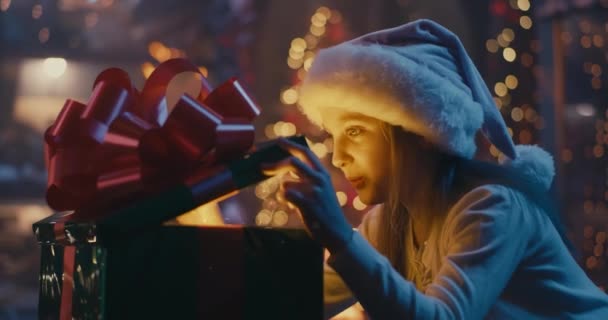 Chica feliz abriendo regalo mágico en la noche de Navidad - Imágenes, Vídeo