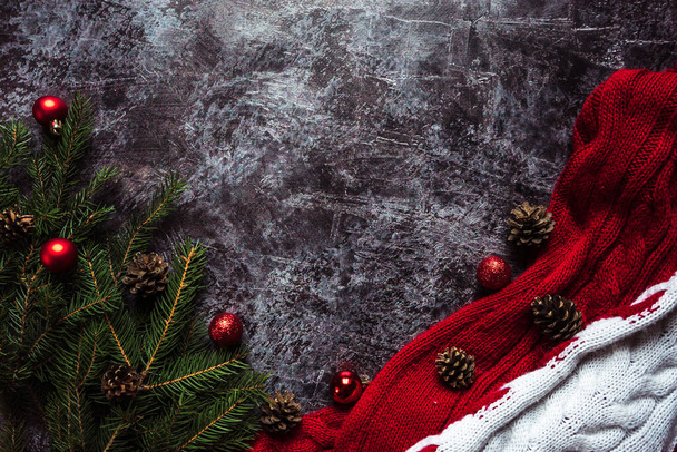 Fondo natalizio per testo con sciarpa rossa lavorata a maglia, addobbi natalizi e pigne e rami 1 - Foto, immagini
