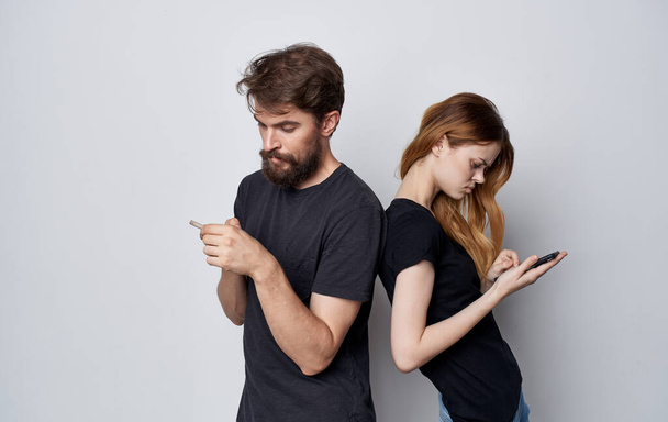 young couple in black t-shirts with phones in hands communication internet technology - Photo, Image