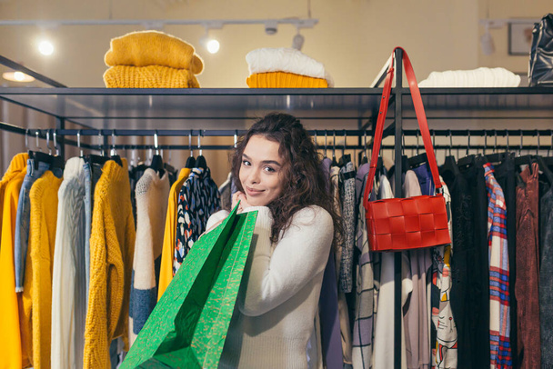 Beautiful girl buyer, buys beautiful stylish clothes in a boutique - 写真・画像