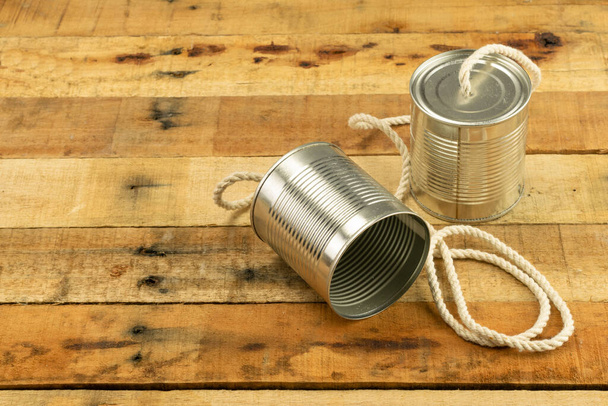 Κονσερβοκούτια ενωμένα με καλώδιο ως τηλέφωνο σε ρουστίκ ξύλινο φόντο - Φωτογραφία, εικόνα