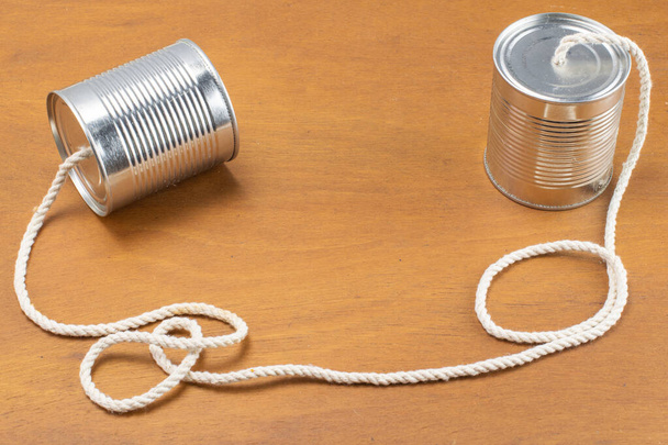 Konserveler ahşap arka planda bir telefon olarak kabloyla birleşir - Fotoğraf, Görsel