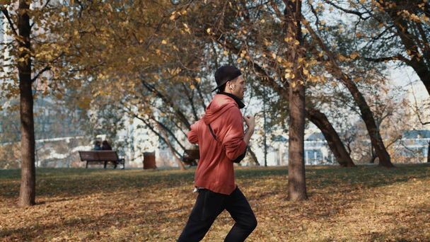 Man runner in sportswear in autumn park in the city, slow motion - Foto, afbeelding
