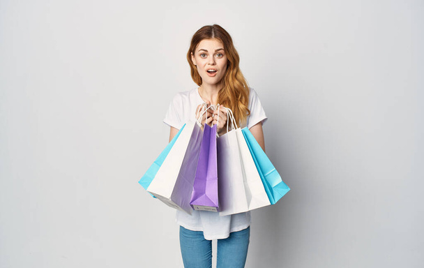 Mujer alegre sosteniendo paquetes de compras en manos aisladas estudio somnoliento - Foto, Imagen
