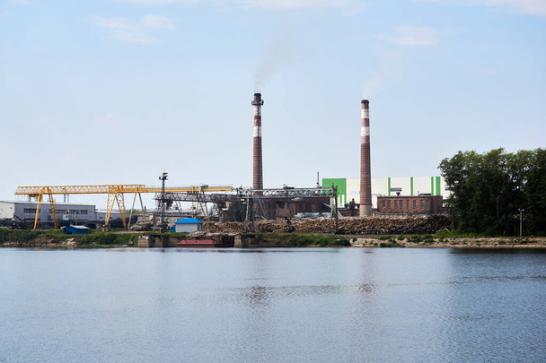 ipari táj, cellulóz- és papírgyár rönkökkel és kéményekkel a folyó mellett - Fotó, kép