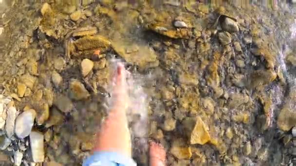 Dívka bosá voda stříkne na kameny mělké řeky zblízka, slunečné léto - Záběry, video
