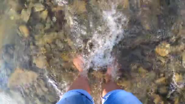 Girl stands barefoot on stones shallow river - Footage, Video