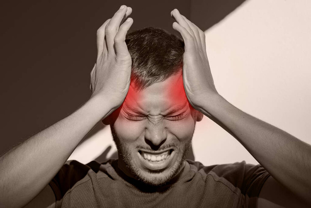 Человек, страдающий от болезненной мигрени или сильной головной боли напряжения. Кластерная головная боль, стресс. Руки за голову. Боль в висках - Фото, изображение