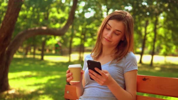twarz młoda kobieta trzyma smartfon SMS na zewnątrz - Materiał filmowy, wideo