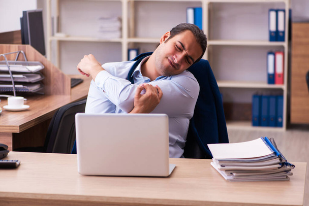 Young male employee stretching at workplace - Photo, Image