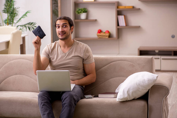 Mladý samec na volné noze drží peněženku doma - Fotografie, Obrázek