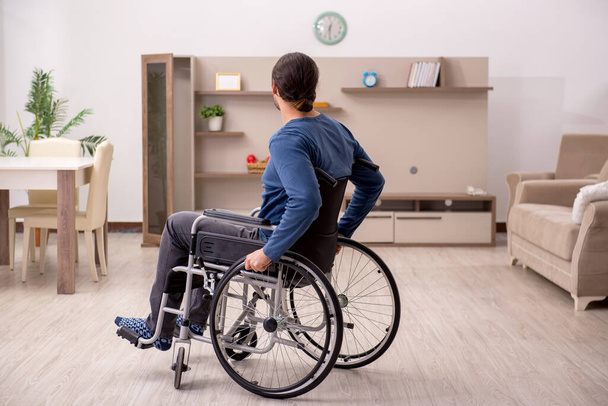 車椅子の若い男が家で苦しんでいる - 写真・画像