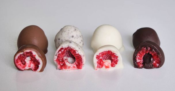 raspberries dipped or covered in mold chocolate cut in half. Different flavors: white chocolate, milk chocolate, dark chocolate and cookies - Photo, Image