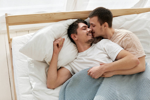 Glücklich gay pärchen liegend auf bett bei zuhause - Foto, Bild