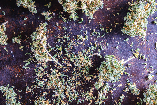 Medicinale cannabisknoppen worden willekeurig verspreid over een roestig metalen oppervlak. horizontale oriëntatie. - Foto, afbeelding