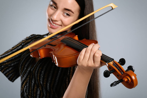 Beautiful woman playing violin on grey background, closeup - Zdjęcie, obraz