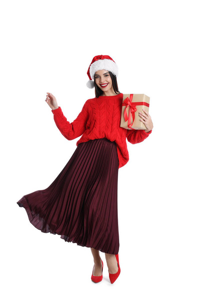Woman in Santa hat and red sweater holding Christmas gift on white background - Fotó, kép