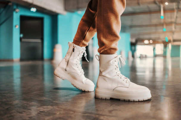 Vystřihnout obrázek módní ženy kráčející v podzemní garáži v bílých botách. - Fotografie, Obrázek