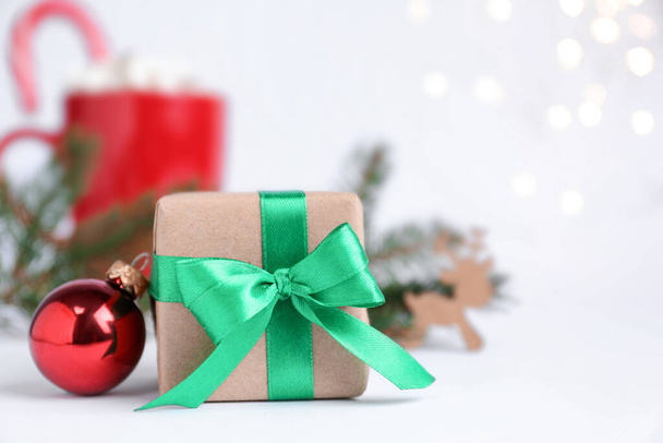 Gift box and Christmas ball on blurred background, closeup. Space for text - Zdjęcie, obraz