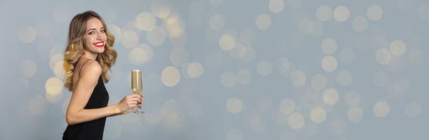 Beautiful woman holding glass of champagne on grey background, space for text. Christmas party, banner design - 写真・画像