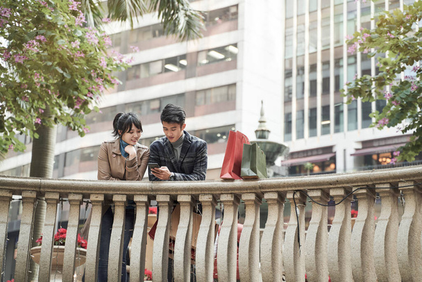 mladý asijský pár navigace pomocí mobilního telefonu při nakupování ve městě - Fotografie, Obrázek