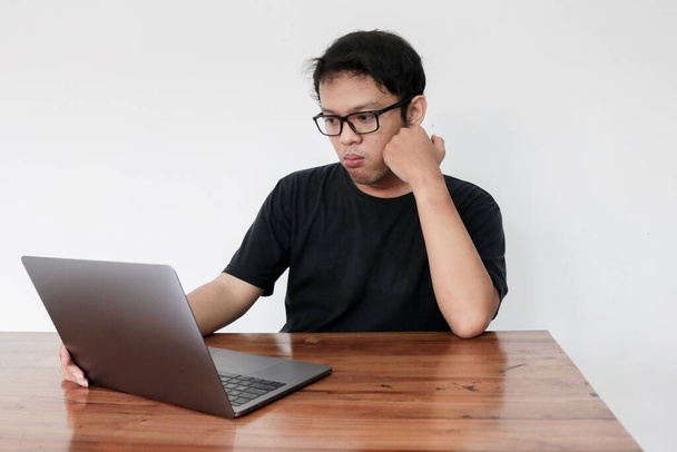 Young asian man is smile and enjoy when working at home with laptop and a cup of coffee. A man sitting on bed and working. Work from home concept. - Foto, afbeelding