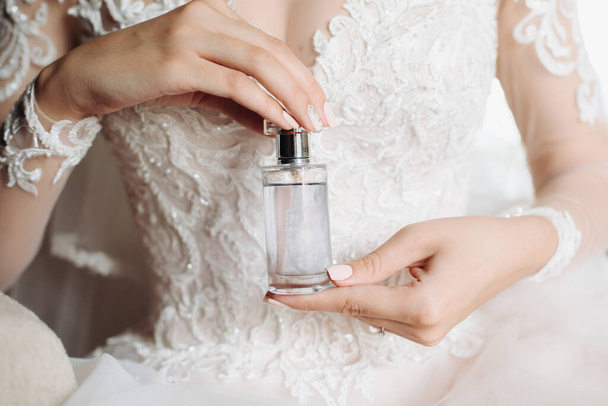 jar of perfume in the hands of the bride. Beautiful wedding manicure.Hands closeup. Wedding morning bride - 写真・画像