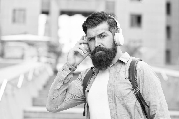 Live life loud with headphones. Hipster wear headphones outdoors. Bearded man listen to music in headphones. New technology. Modern life. Headphones for listening closely - Fotografie, Obrázek