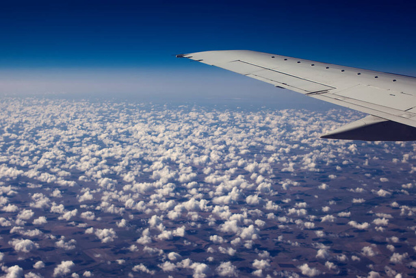 Vleugel van de luchtvlakte vliegen over de wolken met blauwe lucht. - Foto, afbeelding