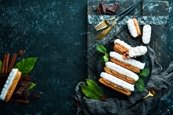 Eclair with cream. Creamy dessert on a black stone plate. Top view. Rustic style. - Фото, изображение