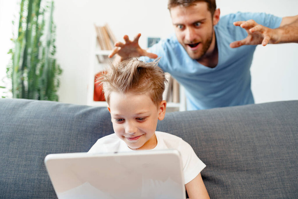 Papà spaventa il suo piccolo figlio whos utilizzando tablet digitale - Foto, immagini