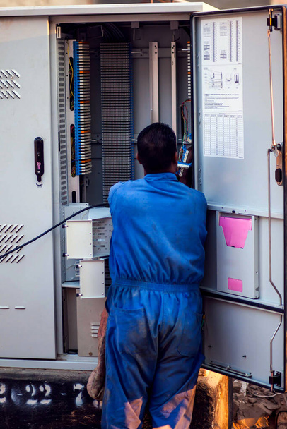 Electricista en ropa de trabajo azul marcando la caja de transformación en la calle - Foto, Imagen