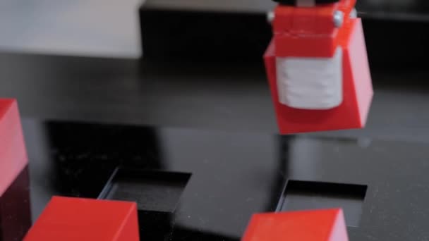 Wybierz i umieść manipulator ramienia robota przesuwając czerwone klocki zabawki na wystawie robotów - Materiał filmowy, wideo
