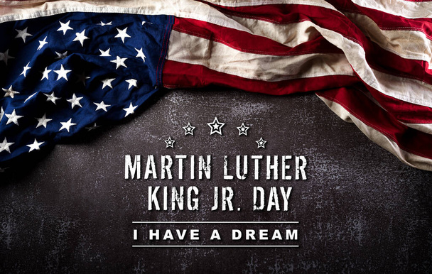 Χαρούμενη ιδέα του Μάρτιν Λούθερ Κινγκ. Αμερικανική σημαία έναντι σκουρόχρωμης πέτρας - Φωτογραφία, εικόνα