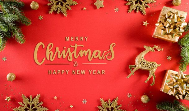 Christmas and new year background concept. Top view of Christmas gift box, spruce branches, pine cones, reindeer, christmas ball and snowflake on red background. - Foto, Imagen