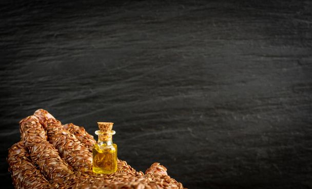 Олія насіння льону в маленькій старовинній пляшці. Постільна білизна текстури фону з ручною і органічною ефірною олією, настойкою, видобутком льон зверху з місцем для текстури
 - Фото, зображення