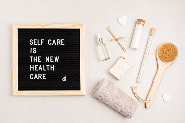 Self care is the new health care. Motivational quote on black letter board with variety of organic body and face care products. Natural homemade eco friendly beauty products concept. Flatlay, top view - Photo, Image
