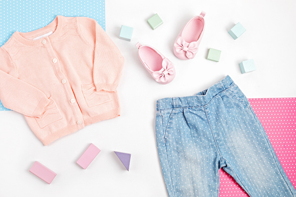 Состав с розовым детским кардиганом, джинсами и туфлями на синем, розовом и белом фоне. Современная концепция женской одежды. Плоский, вид сверху - Фото, изображение