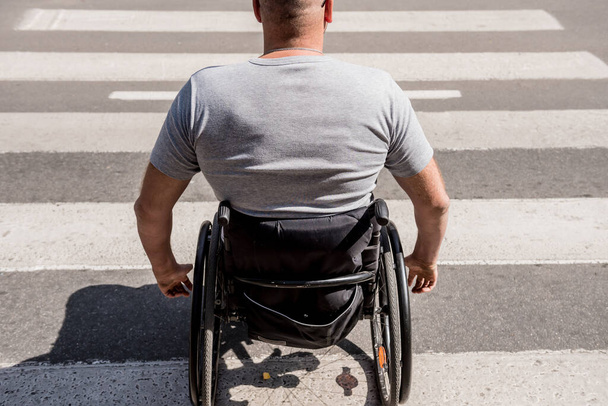 Handicapped man in wheelchair crossing street road - Фото, изображение