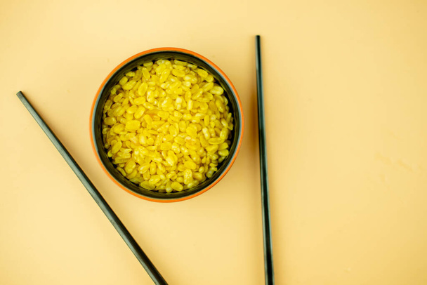 Закрыть золотой цвет хрустящие глубоко жареные бобы Mung в миске на желтом фоне. Тайский аппетитер - Фото, изображение