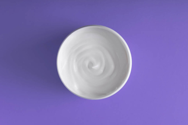 A bowl of sour cream on a purple background. View from above. - Фото, зображення