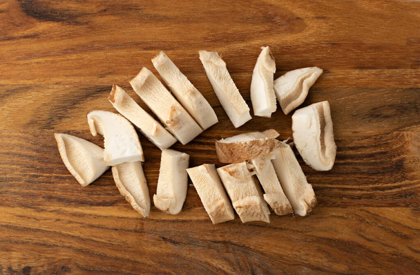 Fresh sliced shiitake mushrooms on wooden cutting board top view. Raw chopped shitake, healthy organic asian fungi - Foto, imagen