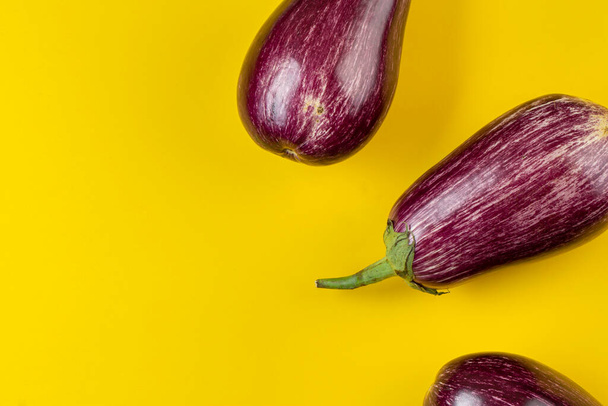 Raw purple eggplant on a yellow background. Fresh vegetables. Space for text. Top view. - Foto, immagini